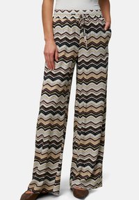 Loose-fitting, patterned trousers featuring a zigzag design in shades of brown, black, and cream. Made of soft fabric with an elastic waistband.
