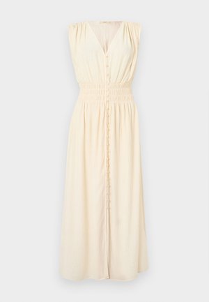 Lichtbeige mouwloze jurk met een V-hals, geplooide schouders en een elastische tailleband. Heeft een knoopsluiting aan de voorkant en een vloeiende zoom.