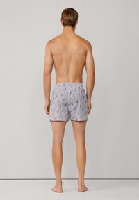 Pantaloni da bagno a righe da uomo in blu e bianco con un motivo giocoso. Vita elastica e vestibilità comoda. Tessuto morbido al tatto.
