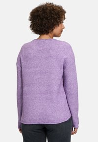 Lila gestrickter Pullover mit einem strukturierten Muster, langen Ärmeln und einem runden Halsausschnitt, der einen etwas längeren hinteren Saum hat.