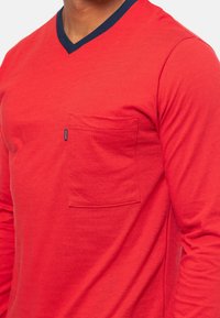Rode lange mouwen shirt met een V-hals en een marineblauwe accenten kraag, voorzien van horizontale strepen en een borstzak aan de linkerkant.
