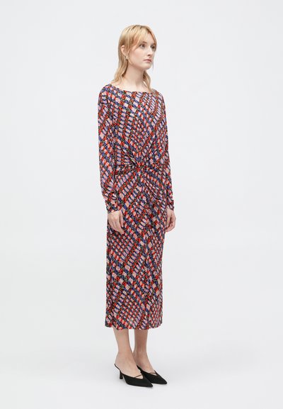 Vestido justo de mangas longas com um padrão geométrico multicolorido em vermelho, azul e preto, com um detalhe em nó na cintura.