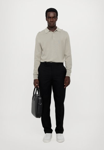 Hellgraues langärmeliges Poloshirt, schwarze maßgeschneiderte Hose, hält eine schwarze Lederhandtasche, weiße Turnschuhe, einfaches Design mit klassischem Kragen.