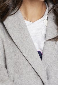 Light grey wool-blend coat with a notched collar, featuring a soft texture and a close-up view of a white t-shirt underneath.