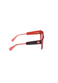 Gafas de sol de plástico rojo con montura rectangular, brazos transparentes y detalles de goma negra en las patillas. Presentan un pequeño logotipo en el lateral.