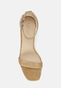 Beige suède hoge hak sandaal met een vierkante neus, enkelbandje en zilveren gespdetail. Glad binnenvoering met reliëf-logo.