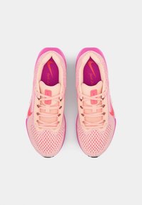 Lichtroze sport schoenen met een mesh bovenwerk, roze accenten en een rubberen zool. Voorzien van roze veters en een "just do it" logo in oranje.