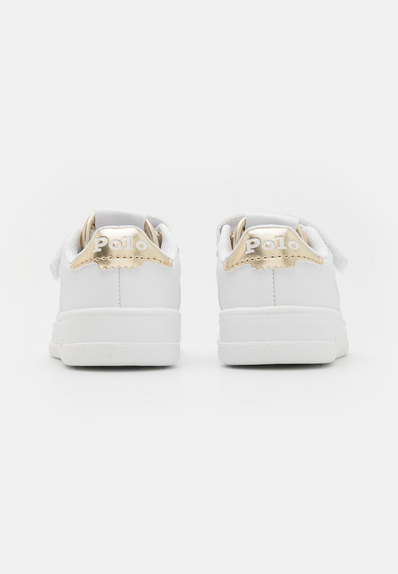 Des baskets blanches avec un dessus en cuir lisse, des accents dorés contrastants sur le talon et un logo "Polo" en relief à l'arrière. Semelle extérieure texturée blanche.