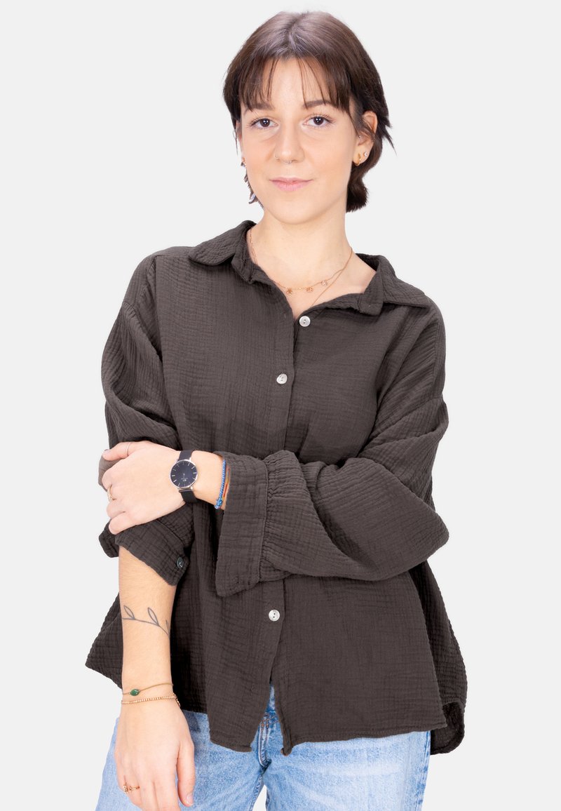 Dark gray, textured button-up shirt with a collar and long sleeves, paired with light blue jeans and layered bracelets.