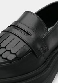 Svart skinnloafer med et teksturert heksagonalt mønster på overlæret, subtil søm og en jevn finish. Rund tå og lavprofil såle.