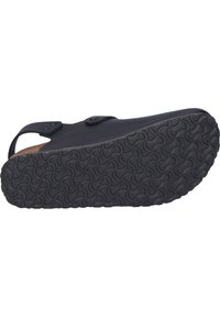 Black footwear with a smooth upper, two adjustable straps with round buckles, and a textured rubber sole featuring a wavy pattern.