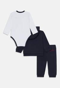 Långärmad vit body, marinblå hoodie med röd logotyp och marinblå jumprar. Bomullstyg. Med huva, avslappnad passform, ribbade muddar.