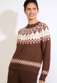 Hnedý pletený sveter z ľahkej textúrovanej tkaniny. Na prievlaku a leme sú geometrické vzory v krémovej, ružovej a tmavo hnedej farbe.