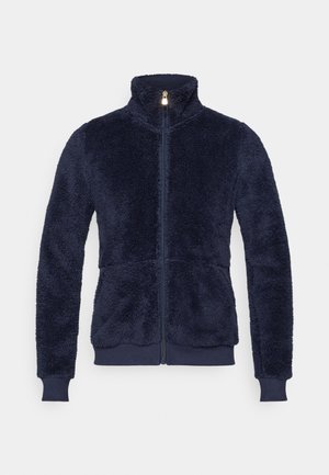 Tamsiai mėlyna vilnos striukė su aukštu apykakle, užtrauktuku per visą ilgį ir nertais rankogaliais. Minkšta, tekstūruota medžiaga su šiek tiek priderintu siluetu.