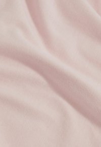 Tissu en coton rose clair avec une texture lisse, présentant des plis doux et un motif de surface uniforme. Aucun accessoire métallique ni accent notable présent.