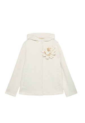 Veste à capuche blanche avec une finition texturée, arborant une application florale décorative sur le côté gauche et deux poches avant.