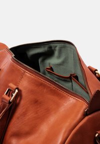 Braune Ledertasche mit goldfarbenen Beschlägen, ausgestattet mit grünem Stofffutter, Reißverschluss und Innentaschen zur besseren Organisation.