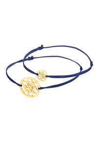 Colgantes de metal tono dorado en cordones azules. El colgante circular grande presenta un patrón de corte geométrico; el colgante más pequeño es similar en diseño.