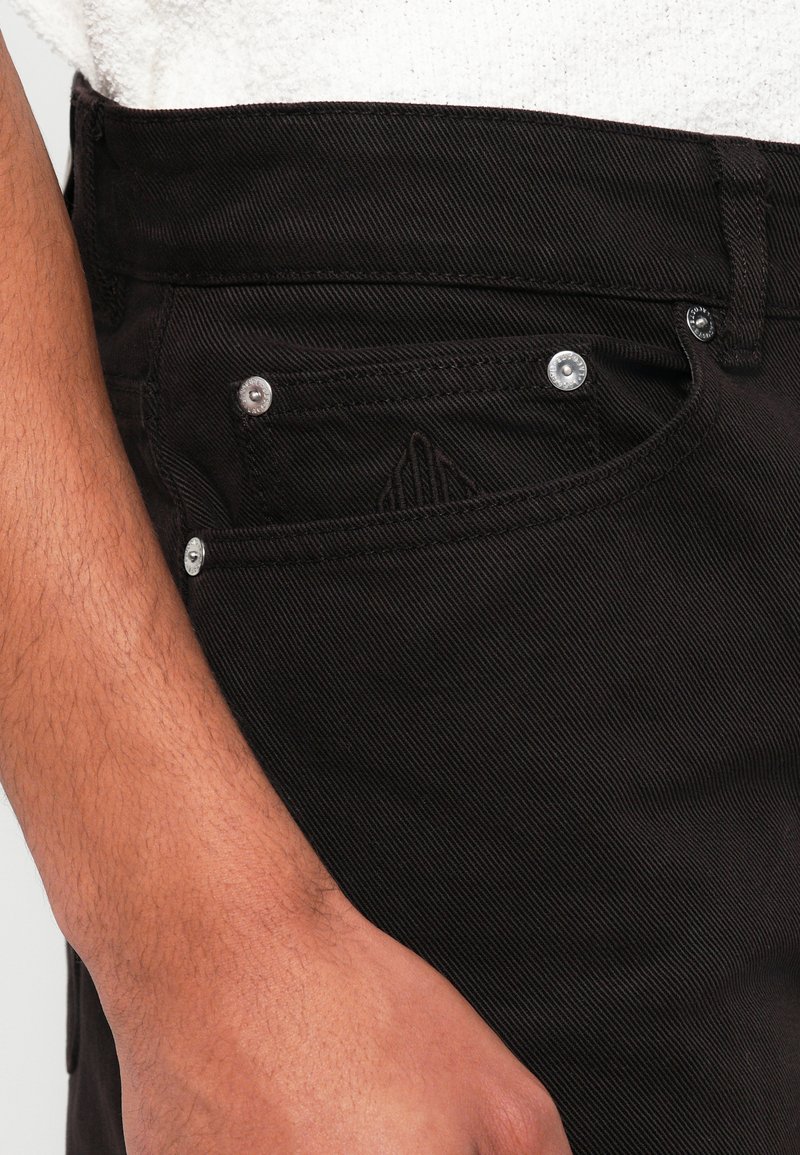 I jeans in denim neri presentano una superficie testurizzata, accessori in argento sulle tasche e un dettaglio del logo tono su tono sulla tasca anteriore.