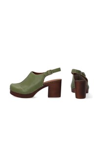 Groene leren hoge klompen met een ronde neus, een slingbackbandje en een bruine houten hak. Heeft zichtbare stiksels langs de randen.