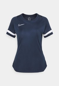 Tummansininen Nike Dri-FIT urheilupaita, jossa valkoiset yksityiskohdat hihoissa. Lyhythihainen, pyöreä kaula-aukko ja vartalonmyötäinen muotoilu. Sileä ja kevyt kangas.