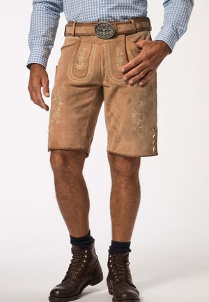 Pantalones cortos de cuero marrón con bordados decorativos, cinturón con hebilla de plata y acentos de botón en el lateral. Usados con botas marrones y calcetines.