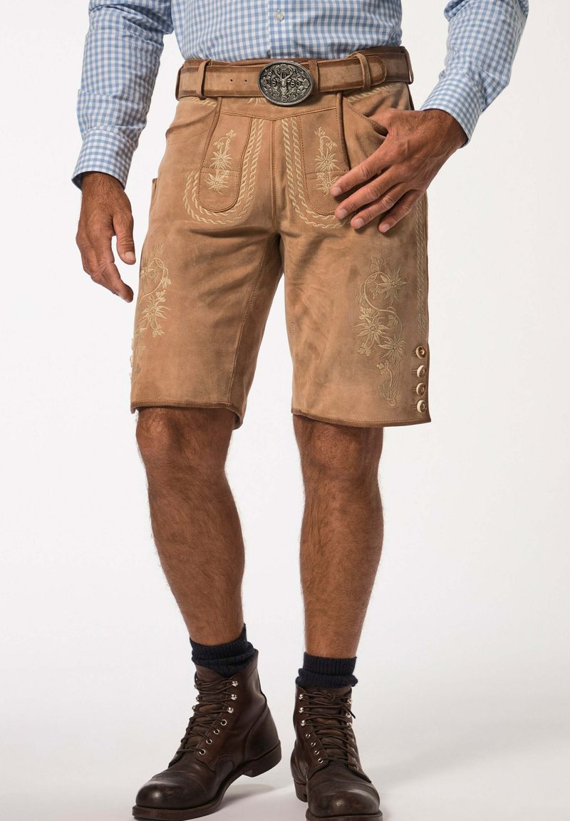 Pantalones cortos de cuero marrón con bordados decorativos, cinturón con hebilla de plata y acentos de botón en el lateral. Usados con botas marrones y calcetines.