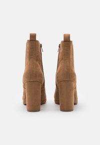 Ruskeat mokkanahkaiset nilkkurit, joissa on korkea paksu korko ja sivuvetoketju, sileä pinta ja vähäiset ompelusaumat.