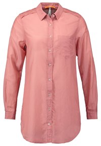 Långärmad skjorta med knappframsida i mjuk rosa tyg, med en framficka, krage och rundad nederdel. Slät textur med glänsande knappar.