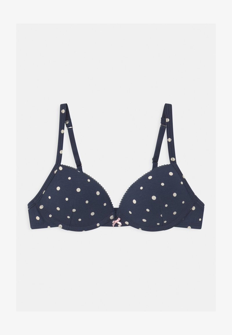 Navy bra with gold polka dots, lace trim along the edges, and a small pink bow accent at the front center. Adjustable straps.
