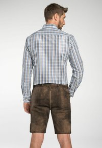 Heren geruite shirt in blauw en wit met lange mouwen, gecombineerd met bruine suède shorts met zijzakken en een gestructureerde afwerking.