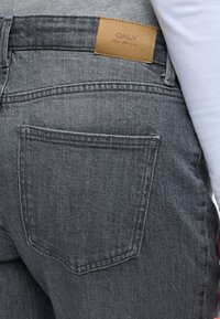 Γκρι τζιν από denim με υφή, διαθέτοντας πίσω τσέπες και καφέ δερμάτινη ετικέτα με την ένδειξη "ONLY". Απλός, κλασικός σχεδιασμός.