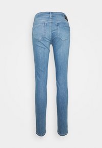 Jeans ajustados en denim azul claro, con una cintura estándar, dos bolsillos traseros y costuras mínimas. Textura suave y acabado liso.