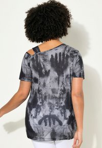 Top a maniche corte nero e grigio tie-dye, con un taglio asimmetrico e dettaglio sulla spalla, realizzato in un tessuto morbido e testurizzato.