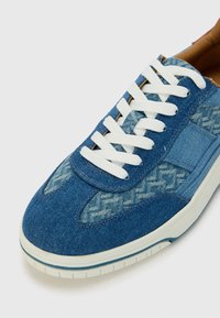 Baskets en denim avec une palette de couleurs bleues, des lacets blancs, des accents texturés et une semelle en caoutchouc au design imprimé.