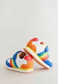 Lasten lenkkitossut, joissa valkoinen pohja, oranssi kantapää, sateenkaaren värit raidat, sininen kärki ja hihna, keltainen välipohja ja kuminen ulkopohja neutraalilla taustalla.