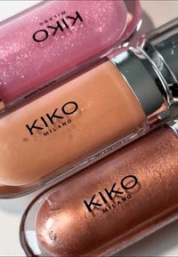 Tre KIKO Milano läppglans i tuber: rosa, persika och brons. Var och en har en glänsande finish och visar tydligt varumärket.