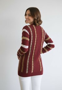 Sweter dziergany z bordowymi i złotymi paskami oraz białymi akcentami. Materiał o fakturze, długie rękawy i luźny krój. Szczegółowy wzór na plecach.