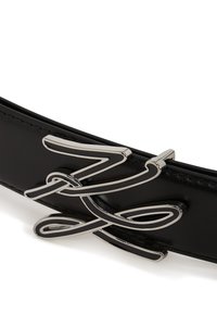 Zwarte leren riem met een glanzende afwerking en een zilveren metalen gesp met een golvend ontwerp, die ingewikkelde details en een soepele textuur toont.