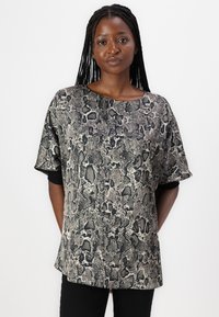 Kortärmad topp i ormskinnsmönster med en neutral färgpalett av beige och svart, med en avslappnad passform och rund halsringning.