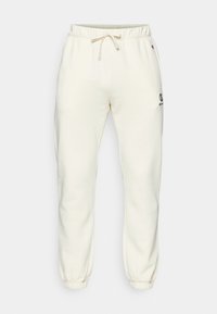 Pantalons de jogger de couleur crème en tissu doux, dotés d'une taille élastique avec cordon de serrage, de poignets ajustés et d'un petit logo sur le côté.