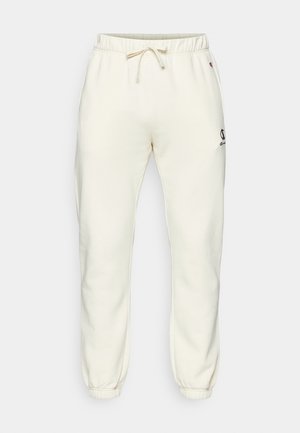 Cream-colored jogger pants made of soft fabric, featuring an elastic waistband with drawstring, fitted cuffs, and a small logo on the side.