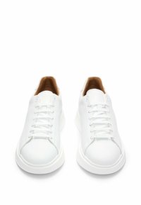 Paire de baskets basses en cuir blanc avec lacets blancs et doublure intérieure marron, vues de face en angle.