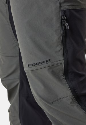 Two-tone outdoor pants featuring a grey fabric with black accents, zippered pockets, and the "SWEDEMOUNT" logo stitched on the side.