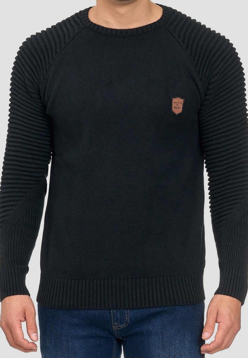 Pull noir en maille avec texture côtelée sur les manches et le corps, col rond classique, et une petite pièce en cuir sur la poitrine.