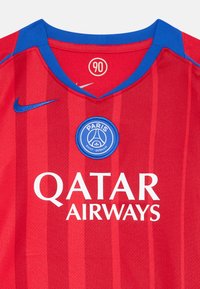 Červený športový dres s vertikálnymi pruhmi, modrý golier a logo Nike. Stredná okrúhla nášivka obsahuje "PARÍŽ" nad "SAINT-GERMAIN" a "QATAR AIRWAYS."