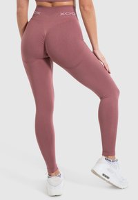 Leggings a vita alta in mauve, realizzati in tessuto elastico. Presentano una superficie liscia e un dettaglio con logo sulla vita.