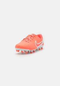 Des chaussures de football avec un dessus rose vif, des accents blancs et des crampons en caoutchouc. Présente un design texturé et des lacets pour un maintien sécurisé.