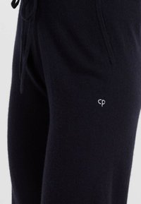 Joggers blu navy realizzati in tessuto morbido, con vita regolabile e piccolo logo "cp" bianco sulla coscia. Tessuto liscio con vestibilità slim.