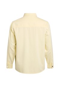 Pohľad zozadu na svetložltú košeľu s dlhými rukávmi, gombíkové manžety a rovný golier.